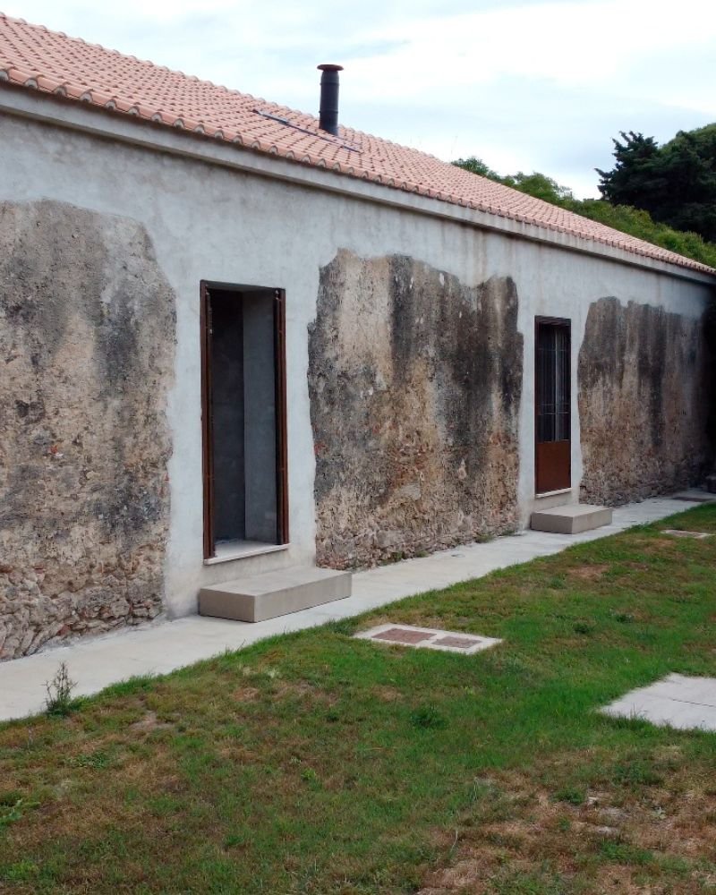 Facciata di casa storica restaurata, con pareti in pietra a vista e dettagli in intonaco chiaro