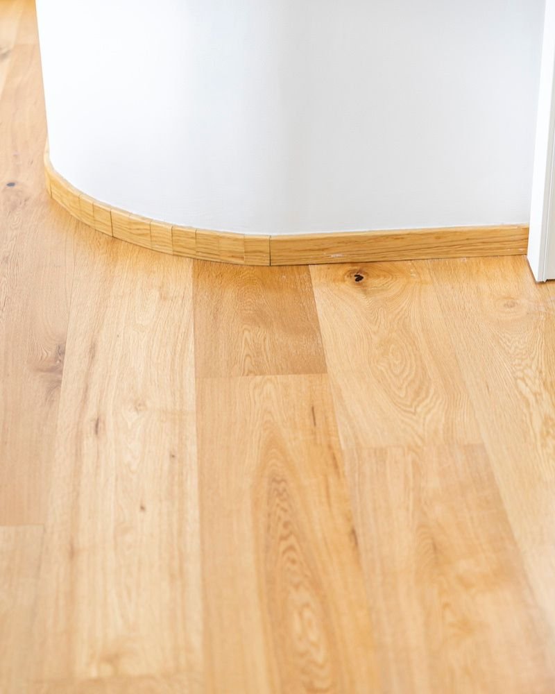 Dettaglio del parquet in legno chiaro su una curva architettonica interna, in abitazione costruita in muratura
