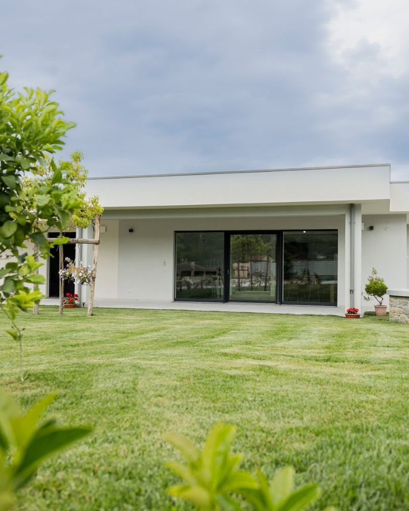 Casa in muratura bianca con ampio prato e tetto a sbalzo dal design lineare