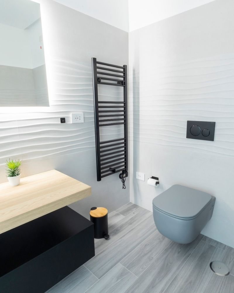 Dettaglio di bagno contemporaneo con piastrelle chiare, arredi minimalisti e sanitari sospesi in una casa in muratura