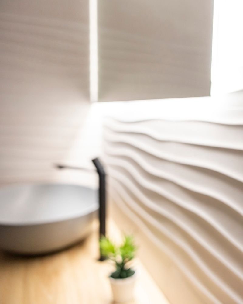 Ambiente bagno sfocato con lavabo in primo piano e decorazioni murarie, ideale per interni in muratura